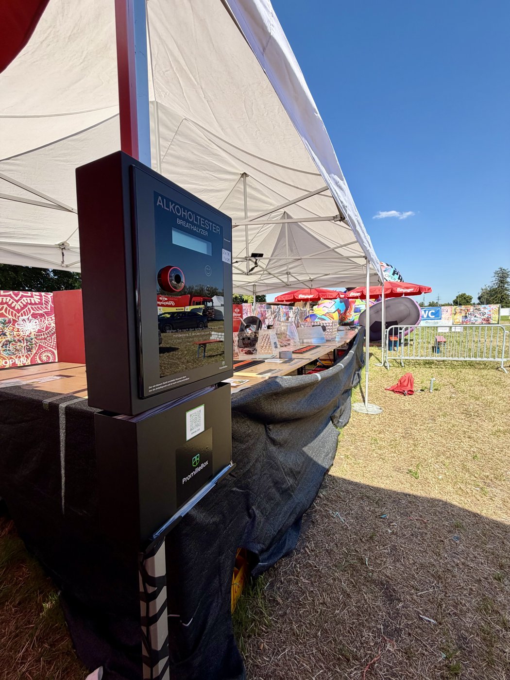 PromilleBox am Festivalstand unter einem Zelt, mit Blick über das sonnige Festivalgelände